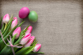 Tulpen und Ostereier auf braunem Stoff Hintergrund.