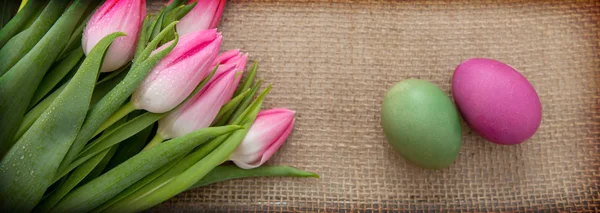 Tulips and easter Eggs on brown cloth Background. — Stock Photo, Image