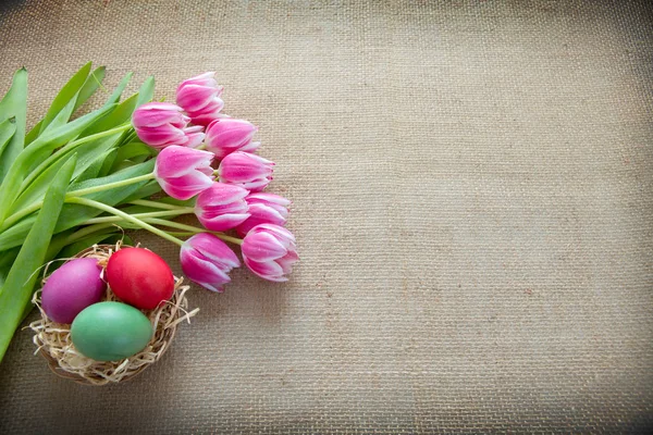 Тюльпани та великодні яйця на коричневій тканині Фон . — стокове фото