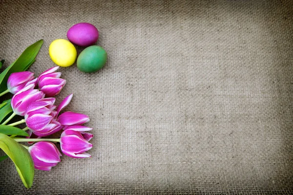 Тюльпани та великодні яйця на коричневій тканині Фон . — стокове фото