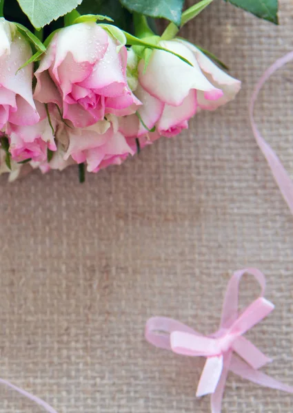 Roze rozen en lus geïsoleerd op bruin doek achtergrond. — Stockfoto