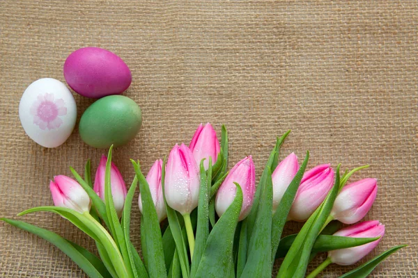 PinkTulips and Easter Eggs on brown cloth Background. — Stock Photo, Image
