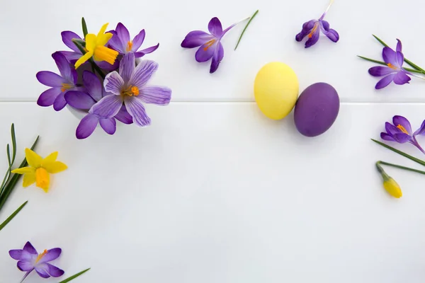 Crochi viola e uova di Pasqua isolato su sfondo di legno bianco . — Foto Stock