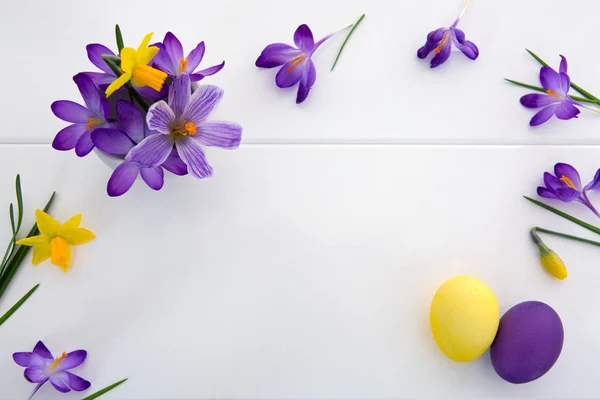 Crochi viola e uova di Pasqua isolato su sfondo di legno bianco . — Foto Stock