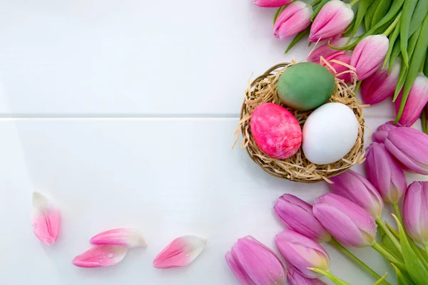 Tulipani e Pasqua Uova nel nido isolate su legno bianco Fondo . — Foto Stock