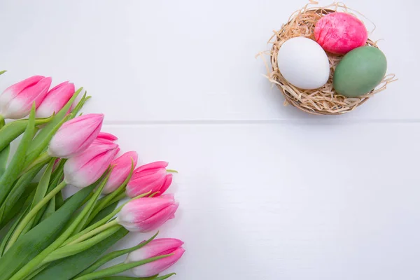 Tulipani e Pasqua Uova nel nido isolate su legno bianco Fondo . — Foto Stock