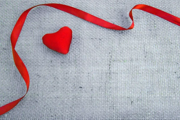 Czerwone serce i wstążka izolowane na szarym tle tkaniny. — Zdjęcie stockowe