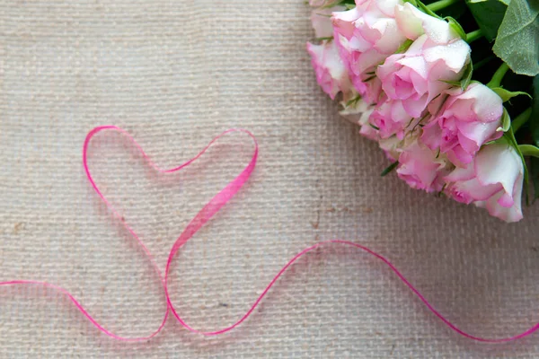 Rosa Herzband und Rosen isoliert auf braunem Stoff Hintergrund. — Stockfoto