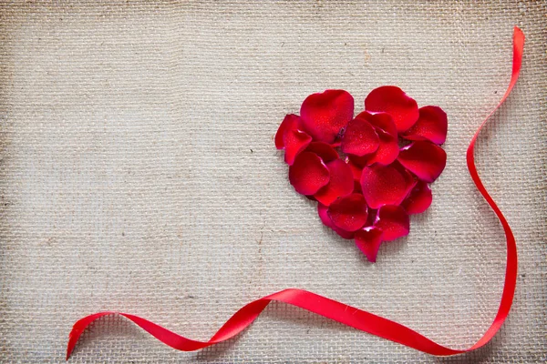천 배경에 고립 된 장미 꽃잎과 루프의 붉은 심장. — 스톡 사진