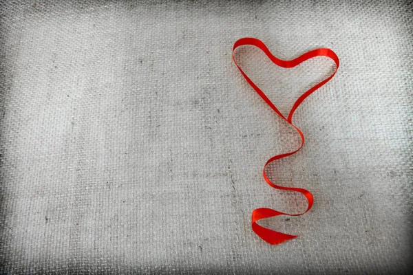 Czerwona wstążka serca izolowana na szarym tle tkaniny. — Zdjęcie stockowe