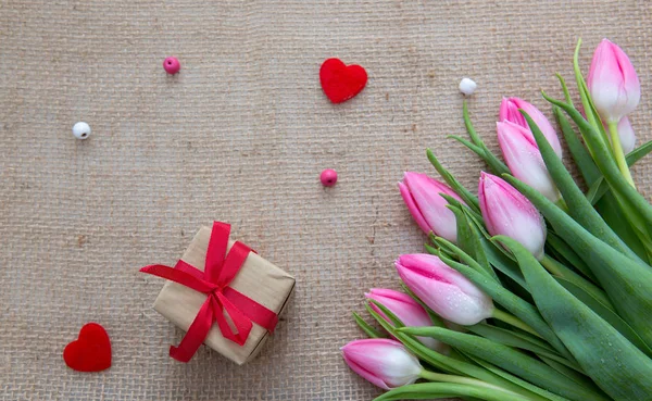 Pink tulips and present isolated on a cloth background. — Stock Photo, Image