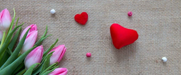 Pink tulips and red hearts isolated on a cloth background. — Stock Photo, Image