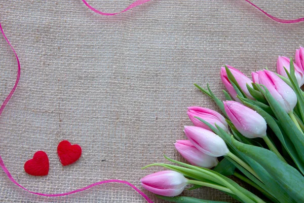 Pink tulips and red hearts isolated on a cloth background. — Stock Photo, Image