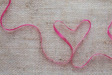 Kırmızı kalp kurdele kahverengi bez arka plan izole.