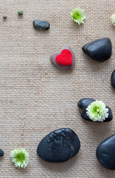 Bir bez arka plan üzerinde aşk kalp, çiçekler ve siyah taşlar ile Spa ayarı. — Stok fotoğraf