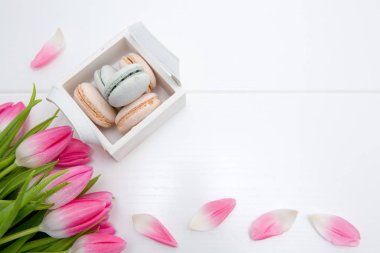 Beyaz arka plan üzerinde sepetpembe lale ve makarna çerezleri.