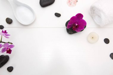 Pembe orkideli spa seti, siyah taşlar ve ahşap arka planda banyo tuzu..