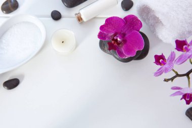 Pembe orkideli spa seti, siyah taşlar ve ahşap arka planda banyo tuzu..