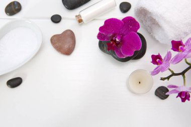 Pembe orkideli spa seti, siyah taşlar ve ahşap arka planda banyo tuzu..
