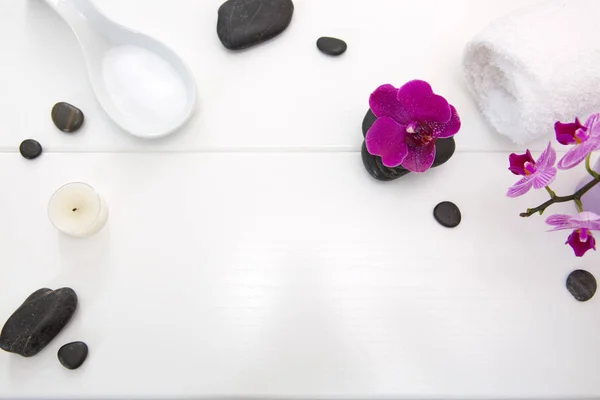 Spa setting with pink orchids , black stones and candle on wood background.