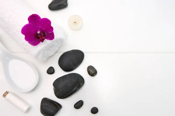 Ambiente spa con orquídeas rosadas, piedras negras y sales de baño  . — Foto de Stock