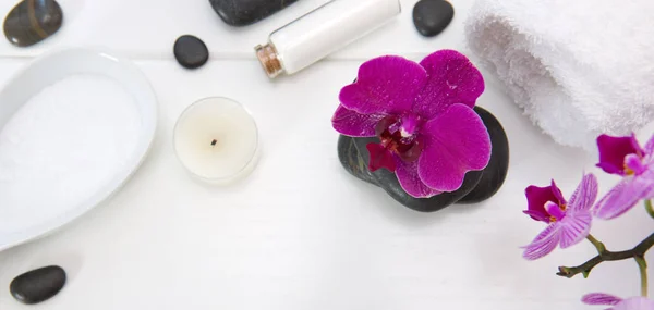 Ajuste de spa con orquídeas rosadas, piedras negras y sales de baño sobre madera blanca  . — Foto de Stock