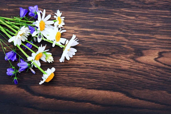 Μπουκέτο με μπλε λουλούδια και λευκές μαργαρίτες σε καφέ φόντο ξύλο. — Φωτογραφία Αρχείου
