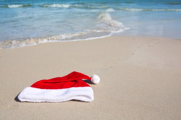 카리빈 해변에서 산타 클로스 모자를 쓰고 있습니다. 크리스마스 배경 — 스톡 사진