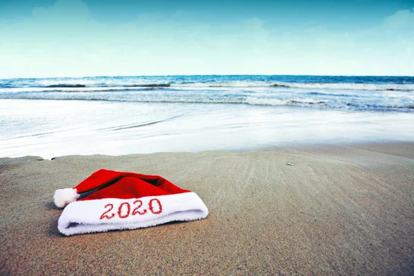 Anno 2020 scritto al cappello di Babbo Natale sulla spiaggia caraibica. Anno nuovo sfondo — Foto Stock