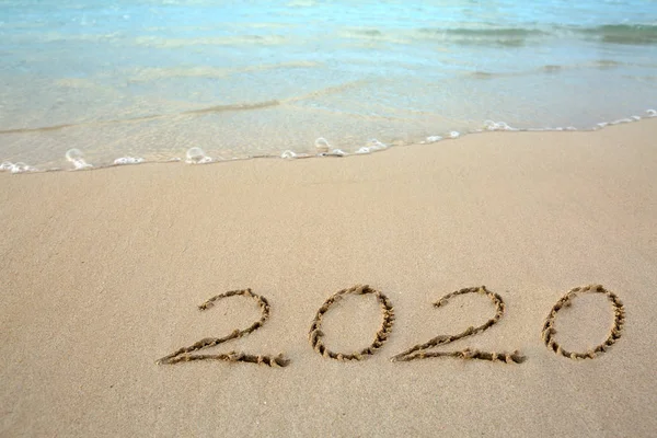 Año 2020 escrito en la playa de arena caribeña con olas marinas  . — Foto de Stock