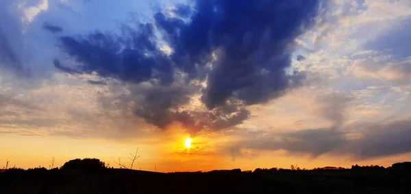 Büyük bulutlar ve ağaçlarla renkli dramatik gün batımı. — Stok fotoğraf