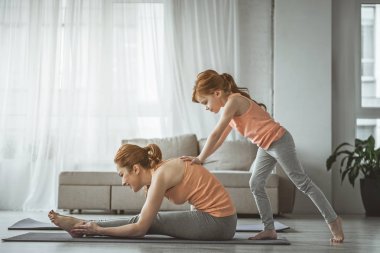 Kızı Anne germe egzersiz yapmak için yardımcı oluyor