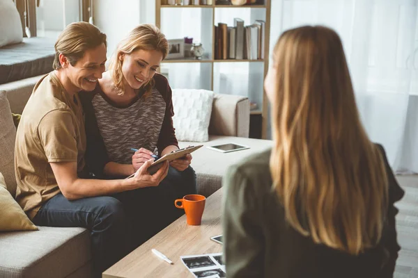 Positive married couple putting signature on surrogate motherhood agreement — Stock Photo, Image