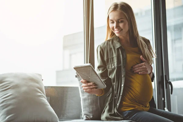 Glad gravid kvinna använda teknik nära fönster — Stockfoto