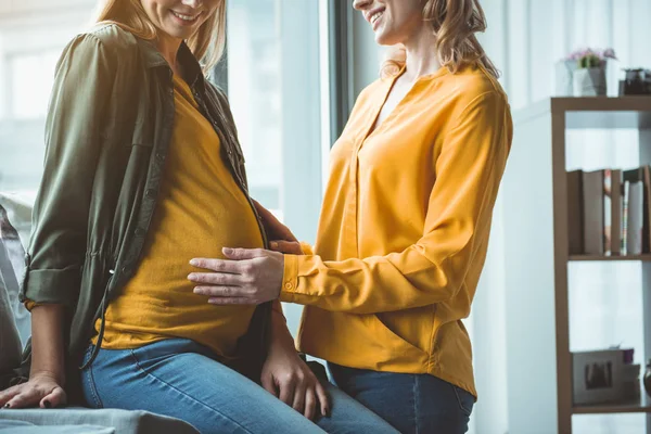 Счастливая женщина поддерживает суррогатную беременную мать — стоковое фото