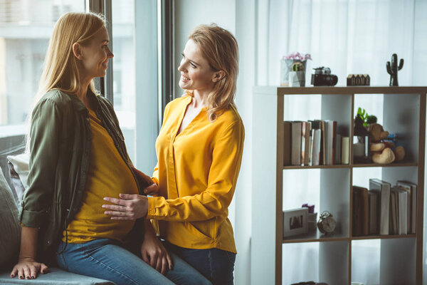 Радостная беременная женщина общается с дамой дома
 