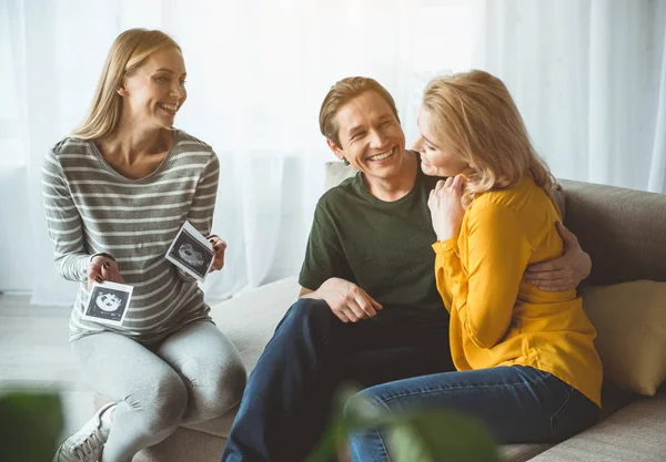 Joyful surrogate expectant mother showing ultrasound picture to couple — Stock Photo, Image