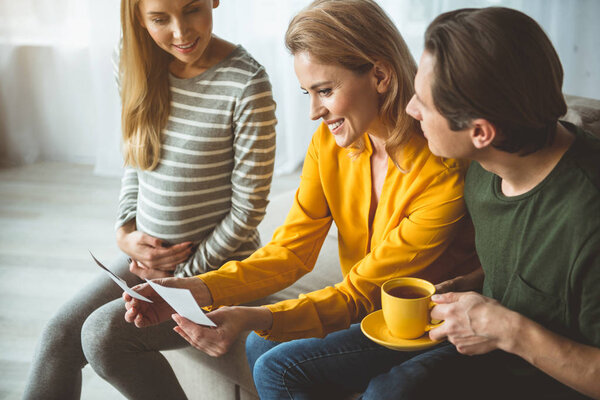 Счастливая беременная женщина показывает фотографию своего нерождённого ребёнка

