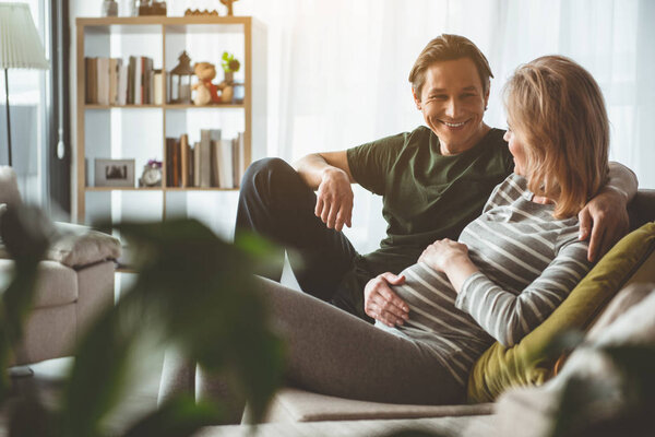 Радостный мужчина обнимает беременную жену с любовью
 