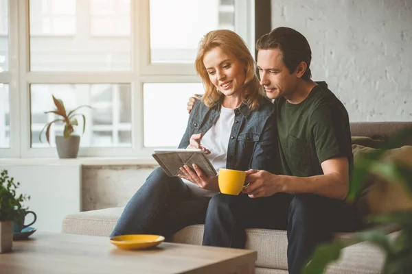 Pareja casada positiva usando gadget en casa — Foto de Stock