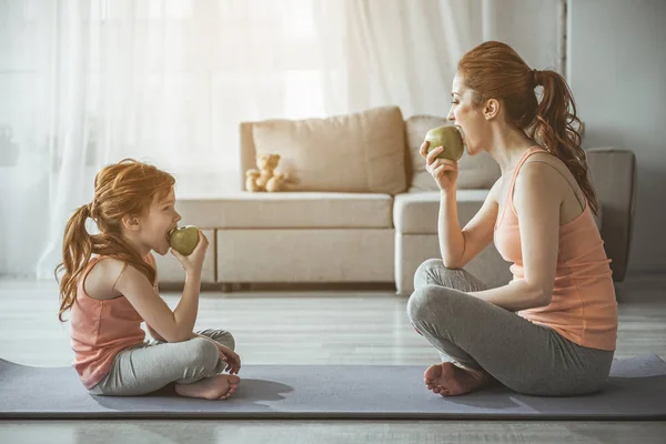 Mujer y niña se miran y comen —  Fotos de Stock