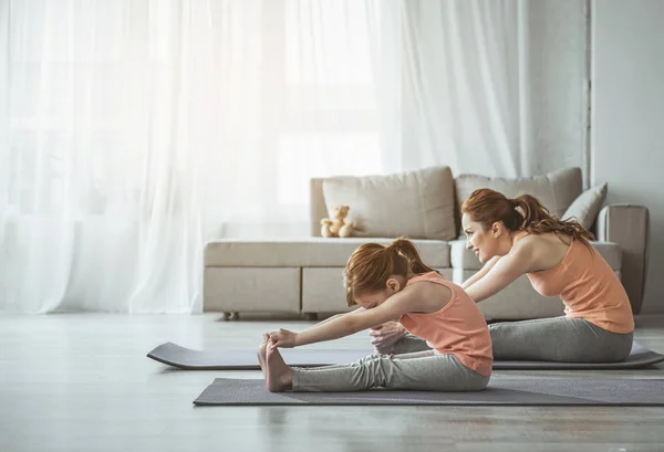 Mãe e menina estão fazendo exercícios de alongamento em casa — Fotografia de Stock