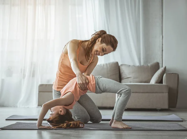 Matka je dcera pomáhá dělat fyzické cvičení doma — Stock fotografie