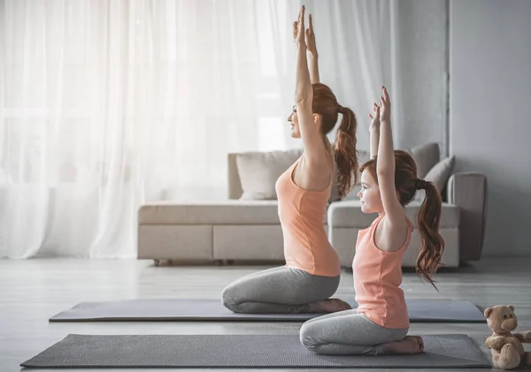 Mãe e menina estão fazendo exercícios esportivos em casa — Fotografia de Stock