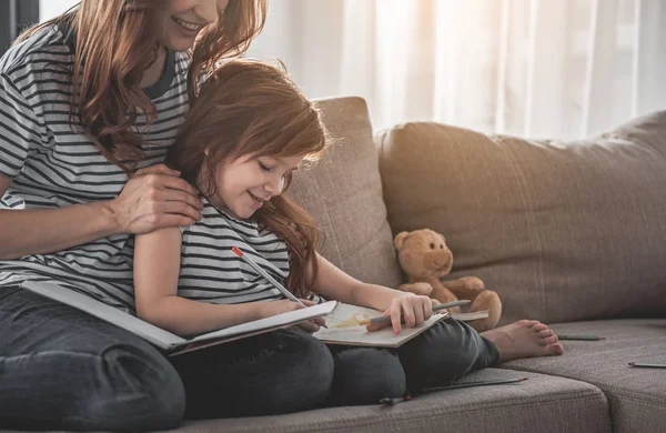Lyckligt barn tillbringar fritid ritning med hennes mamma hemma — Stockfoto