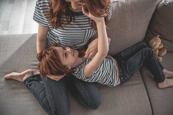 Kärleksfull mamma och barn liggande på soffan i myser — Stockfoto