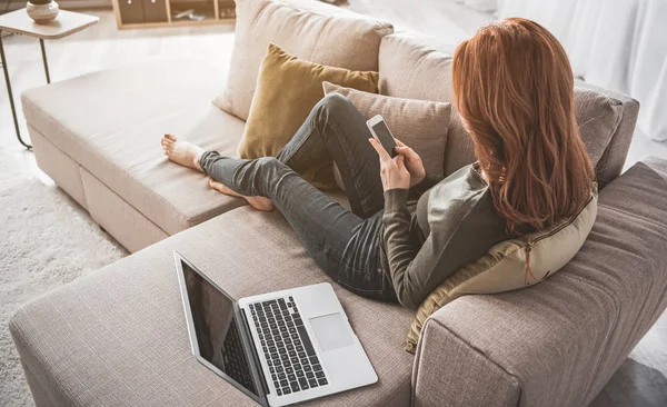 Jovem mulher usando seus gadgets e relaxante em casa — Fotografia de Stock