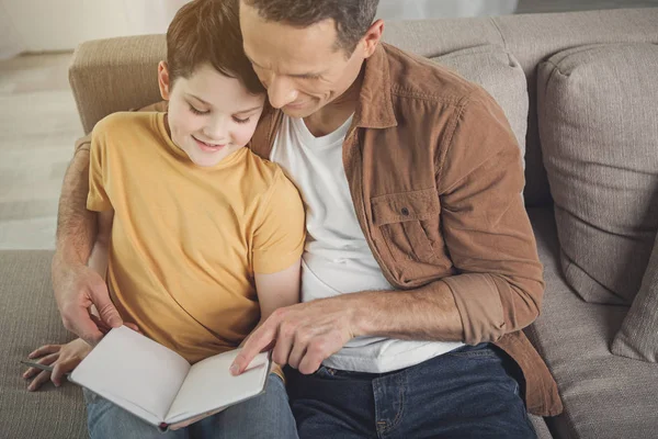 Cheerful parent reading fairy tale for his kid