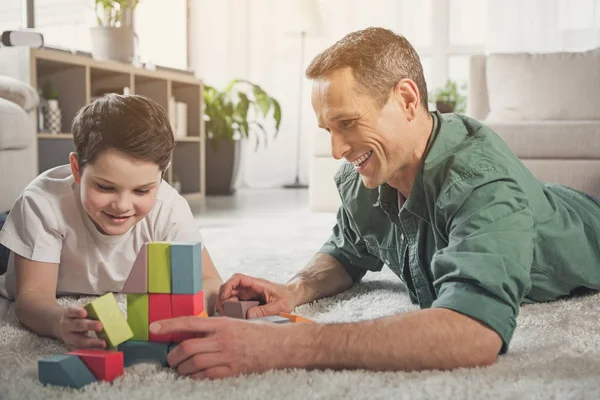 Alegre familia acostada en el suelo y jugando con el juguete — Foto de Stock