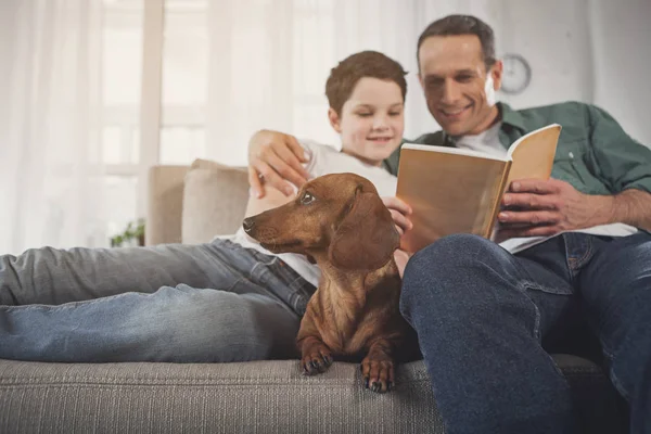 Отец и сын читают книгу возле щенка — стоковое фото